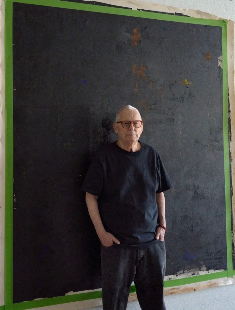 Portrait of David McIntyre standing in front of his art taken by Myron Polenberg.