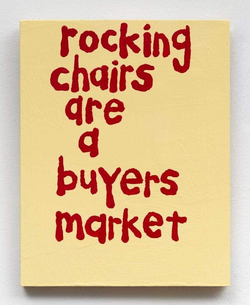 Hand-painted sign reading "rocking chairs are buyers market" in red on yellow background.
