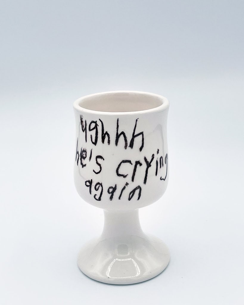 Ceramic cup with handwritten text, part of Cary Leibowitz's art piece.