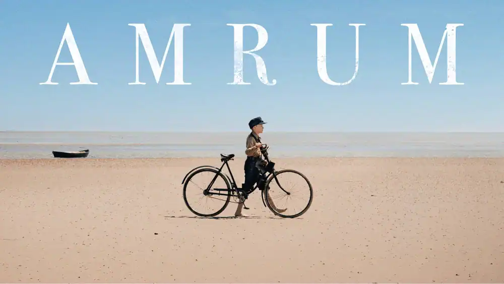 Woman with bicycle on Amrum beach under clear sky.