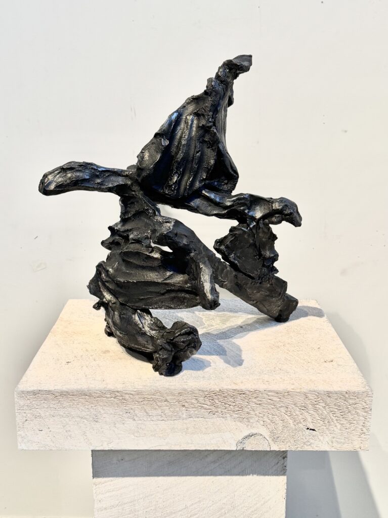 Impossible Wave, black ceramic sculpture by Bruce Edelstein on a white plinth.