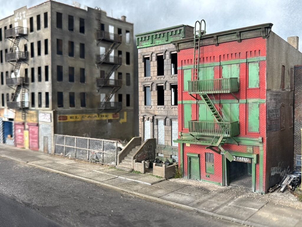 Dennis Gordon sculpture: block of abandoned brick tenement buildings with fire escapes and a rusted car